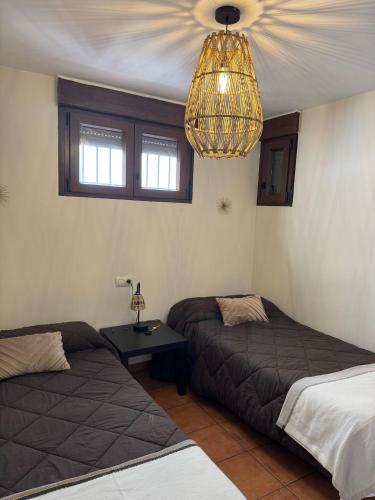 a bedroom with two beds and a chandelier at El Escondite de Aragón in Mora de Rubielos