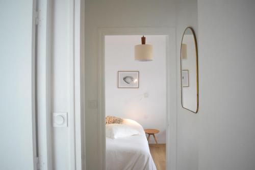 une chambre blanche avec un lit et un miroir dans l'établissement Maison Kermor, à Arzon