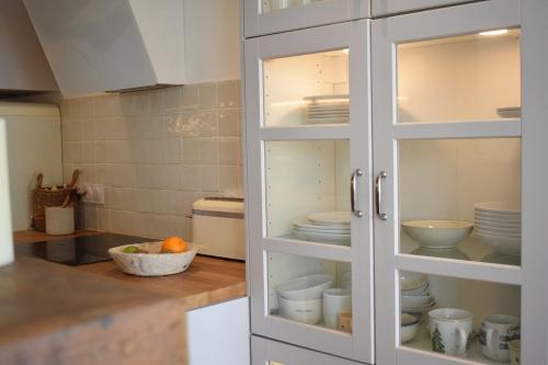 d'une armoire blanche avec de la vaisselle dans la cuisine. dans l'établissement Maison Kermor, à Arzon