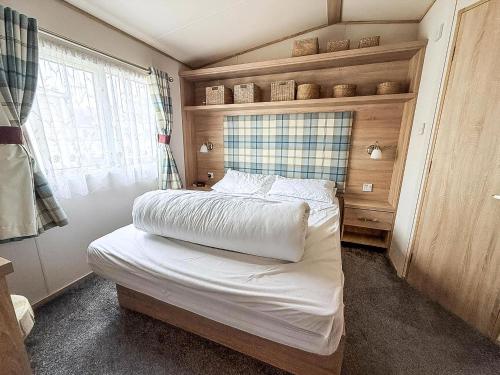 a small bedroom with a bed with white sheets at Beautiful Caravan With Full Sea View At Broadland Sands In Suffolk Ref 20100Bs in Hopton on Sea
