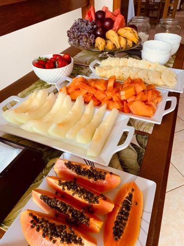 a table topped with plates of food with fruits and vegetables at Pousada Caminho do Mar MADHOUZE in Garopaba