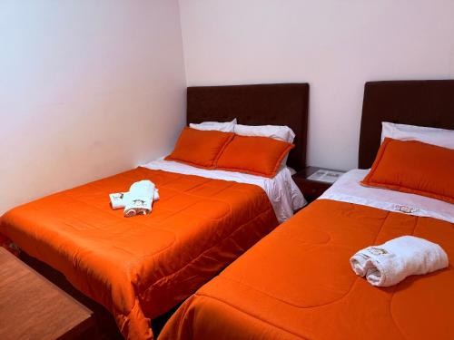 a room with two beds with orange sheets and a stuffed animal on top at HOTEL HOSTERIA la PINTADA in Sáchica