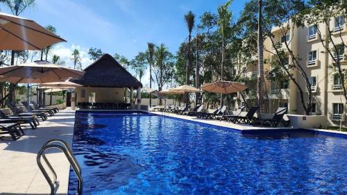 a swimming pool with chairs and umbrellas at a hotel at Casa Bambú, apartment in the best part of Playa del Carmen in Playa del Carmen