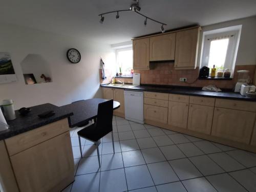 une cuisine avec des armoires en bois et un comptoir noir dans l'établissement Appartement 70m2 Habsheim, près de Mulhouse, à Habsheim