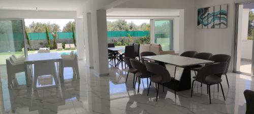 a dining room with tables and chairs and windows at Kiti Village Villa, Cyprus, salt-water pool, 5 bedrooms, Larnaca in Kiti