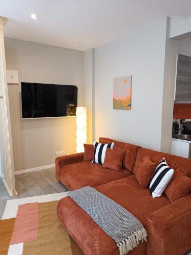 Il comprend un salon doté d'un canapé brun et d'une télévision à écran plat. dans l'établissement La casa amiénoise, à Amiens