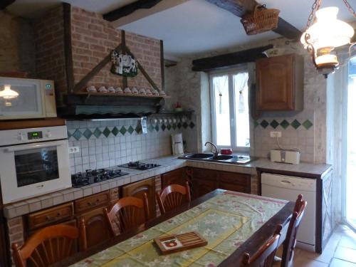 une cuisine avec une table et une cuisinière four supérieur dans l'établissement Gîte de charme piscine, à La Celle-sous-Gouzon