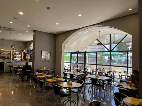 a restaurant with tables and chairs and a large window at Flat em frente ao Allianz Parque in Sao Paulo