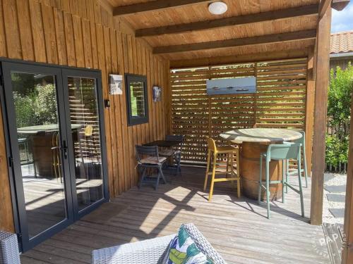 une terrasse en bois avec une table et des chaises dessus dans l'établissement Chalet VIP Ostéa au coeur du Bassin d'Arcachon, à La Teste-de-Buch