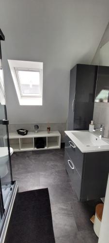 une salle de bain blanche avec un lavabo et une fenêtre dans l'établissement Maison vue mer LES 4 VAGUES, à Saint-Pol-de-Léon