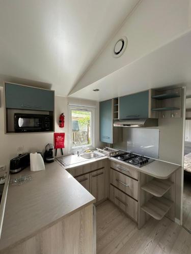 une cuisine avec des placards verts et un comptoir dans l'établissement Mobil Home 6-8p 3ch 2sb Clim, à Seignosse