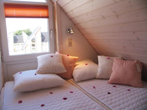 Cama en habitación con almohadas y ventana en Kattegat Strand Camping, en Øster Hurup