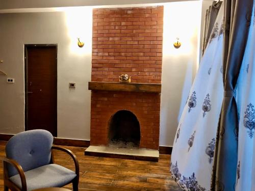 a living room with a brick fireplace and a chair at Zimba Cottage Retreat in Kalimpong