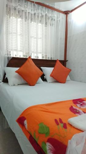 a bedroom with a bed with orange and white pillows at The Shilpa Villa in Unawatuna