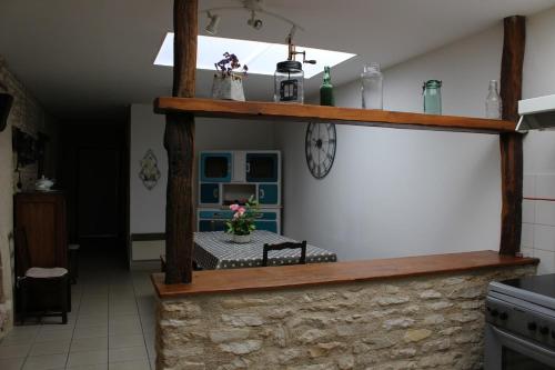 une cuisine avec des étagères en bois et une horloge sur le mur dans l'établissement Les Noyers - Maison typique du Poitou - Calme et paisible - Proche du Futuroscope, à Avanton