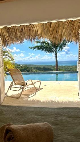a chair and a hammock on a beach with a pool at Villa blanca chambre d'hôtes vue sur mer in Las Terrenas