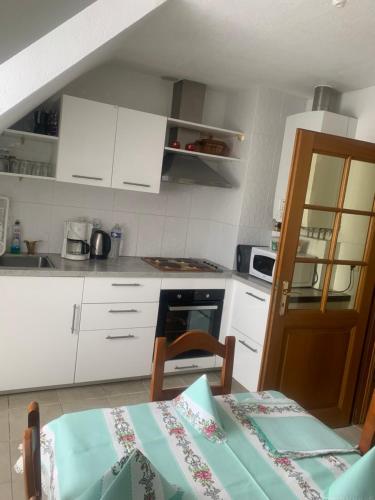 une cuisine avec des placards blancs et une table avec une nappe dans l'établissement Gîte rose, à Colmar