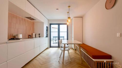 een keuken met witte kasten en een tafel met een kruk bij Villa Frans Lichtrijk appartement 2slpk in Oostende