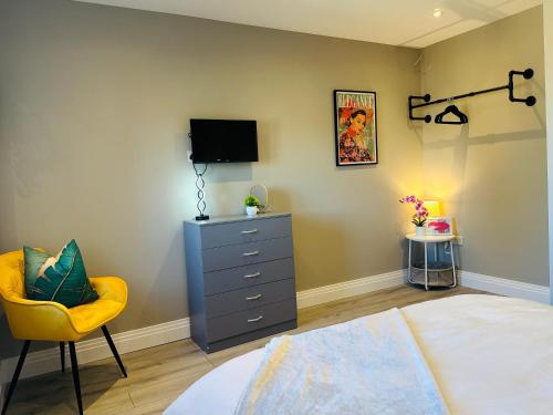 a bedroom with a bed and a dresser and a tv at Travard Heathrow 382 in Harmondsworth