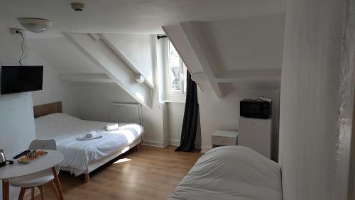 a room with two beds and a table and a window at Quai 8 in Dinan