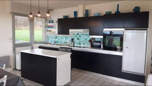 une cuisine avec des armoires noires et un comptoir blanc dans l'établissement Maison vue mer 8 personnes - Finistère Sud, à Moëlan-sur-Mer