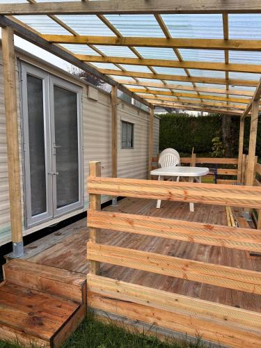 une terrasse en bois avec une pergola et une table dans l'établissement Mobil-home à quelques mètres du lac d'Aiguebelette, à Novalaise