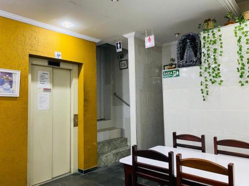 a room with a table and chairs and a yellow wall at Hotel Aparecida do Norte in Aparecida