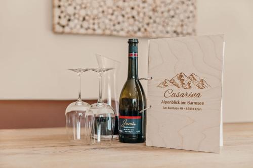 a bottle of wine next to two glasses on a table at CASARINA - Alpentraum am Barmsee mit Garten in Krün
