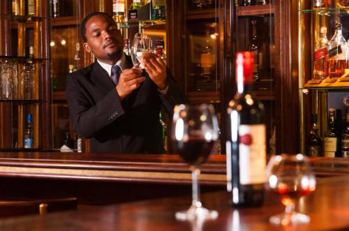 a man in a bar drinking a glass of wine at The Royal Hotel by Coastlands Hotels & Resorts in Durban