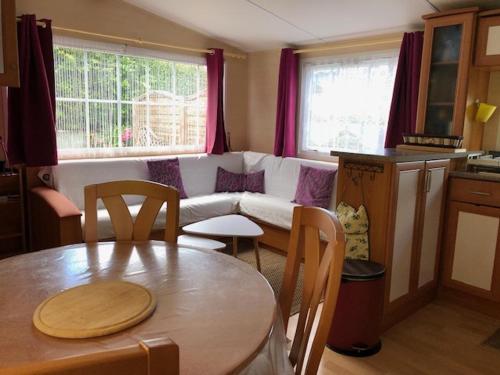 un salon avec une table et un canapé dans l'établissement MOBIL HOME 4 personnes, entre rivière et mer, à Moëlan-sur-Mer