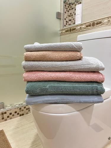 a pile of towels sitting on top of a toilet at Scandinavian Style Apartment in Fergana