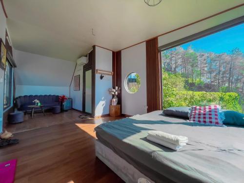 a bedroom with a large window and a large bed at BUNGALOW 2 -phòng săn mây vạn người mê in Tam Ðảo