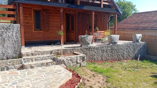 a house with a stone retaining wall and a patio at Brvnara Topilo in Niš