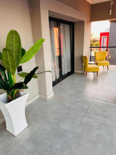a room with a potted plant and a yellow chair at Impèrio Boutique Guest Lodge in Siyabuswa