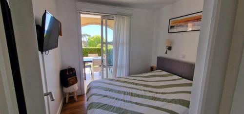 une chambre avec un lit et une télévision et un balcon dans l'établissement T2 Saint-Raphaël, Cap Esterel village, vue mer, rez de jardin, à Saint-Raphaël