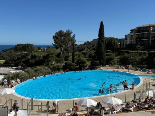 une grande piscine avec des gens dans l'eau dans l'établissement T2 Saint-Raphaël, Cap Esterel village, vue mer, rez de jardin, à Saint-Raphaël