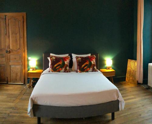 a bedroom with a large bed with two lamps at La Maison aux murs anciens et ses chambres in Tarbes