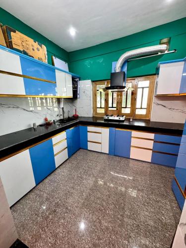 a kitchen with blue and white cabinets and a green wall at Kumaon Lake's Home stay in Nainital