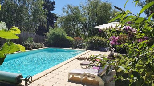 - une piscine dans une cour avec 2 chaises et des fleurs dans l'établissement Charming house in Périgord Vert, à Saint-Félix-de-Villadeix