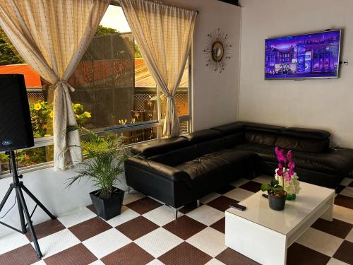 a living room with a black leather couch and a table at Finca de descanso Brisas de Calandaima in Viotá