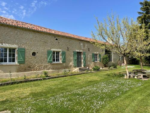a stone house with green shutters and a yard at Domaine de Pourrouquet - Demeure de charme et Gîte in Vic-Fezensac