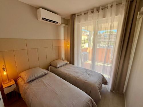 deux lits dans une chambre avec une fenêtre dans l'établissement stunning sea view, à Cavalaire-sur-Mer