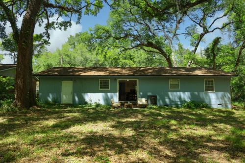 a green house with a tree in the yard at 3 Bedroom Lake House With Garage in Tallahassee