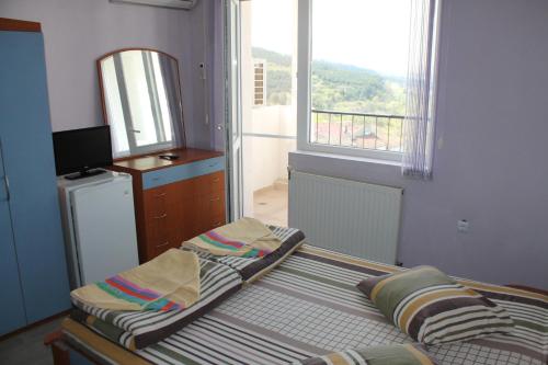a bedroom with a bed and a dresser and a window at Family Hotel Ludo in Varna City