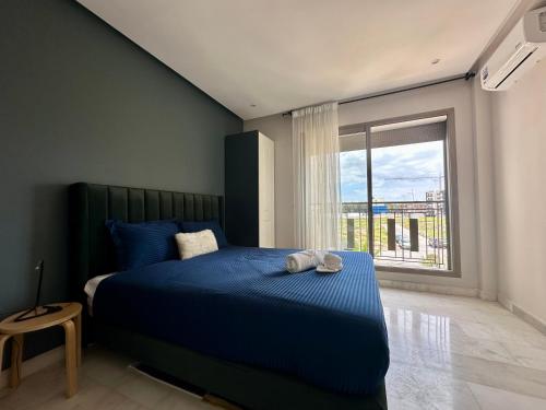 a bedroom with a blue bed with a large window at AeroRelax, free Parking, WI-FI in Nouaseur