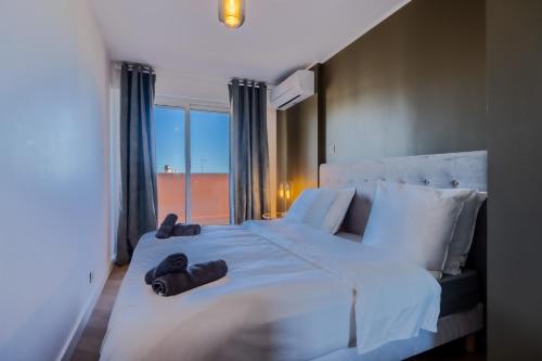 - une chambre avec un grand lit blanc et 2 chaussons dans l'établissement Le Sunrise, à Nice