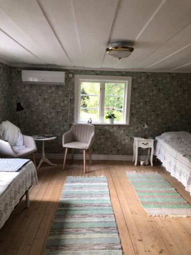 a bedroom with two beds and a window at Mormors stuga har charmigt torrdass och utedusch i trädgården in Möklinta