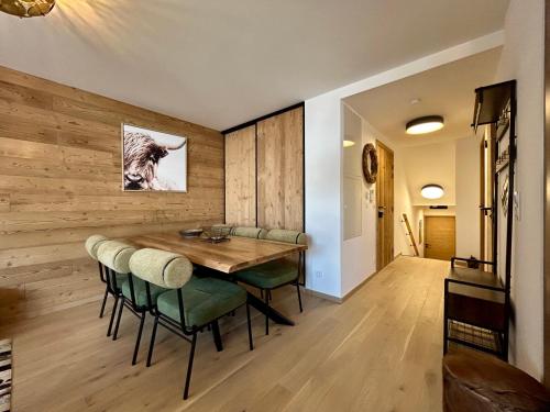une salle à manger avec une table en bois et des chaises vertes dans l'établissement Homency - Résidence L'Expression D21, à L'Alpe-d'Huez