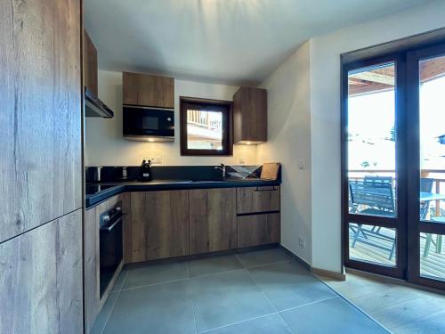 une cuisine avec des placards en bois et une grande fenêtre dans l'établissement Homency - Résidence L'Expression D21, à L'Alpe-d'Huez