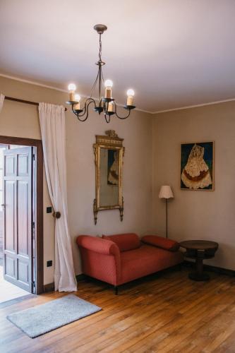 a living room with a red couch and a chandelier at Palacio Conde Toreno in Malleza